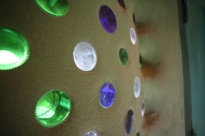 plastered earthship wall with recycled glass bottles and cans